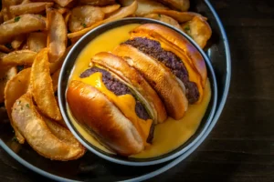 Melt My Heart burger with melted cheese and potato wedges on a plate.