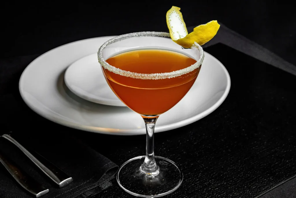 Sidecar cocktail with sugar rim and lemon garnish served in a coupe glass