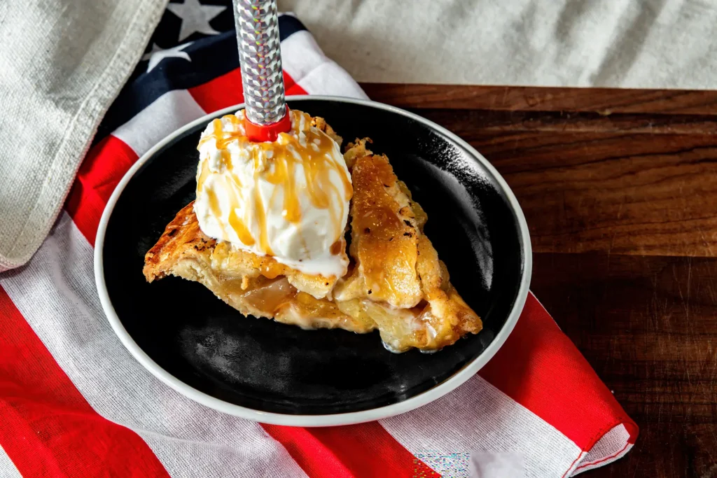 Apple pie à la mode topped with vanilla ice cream and a celebratory sparkler.