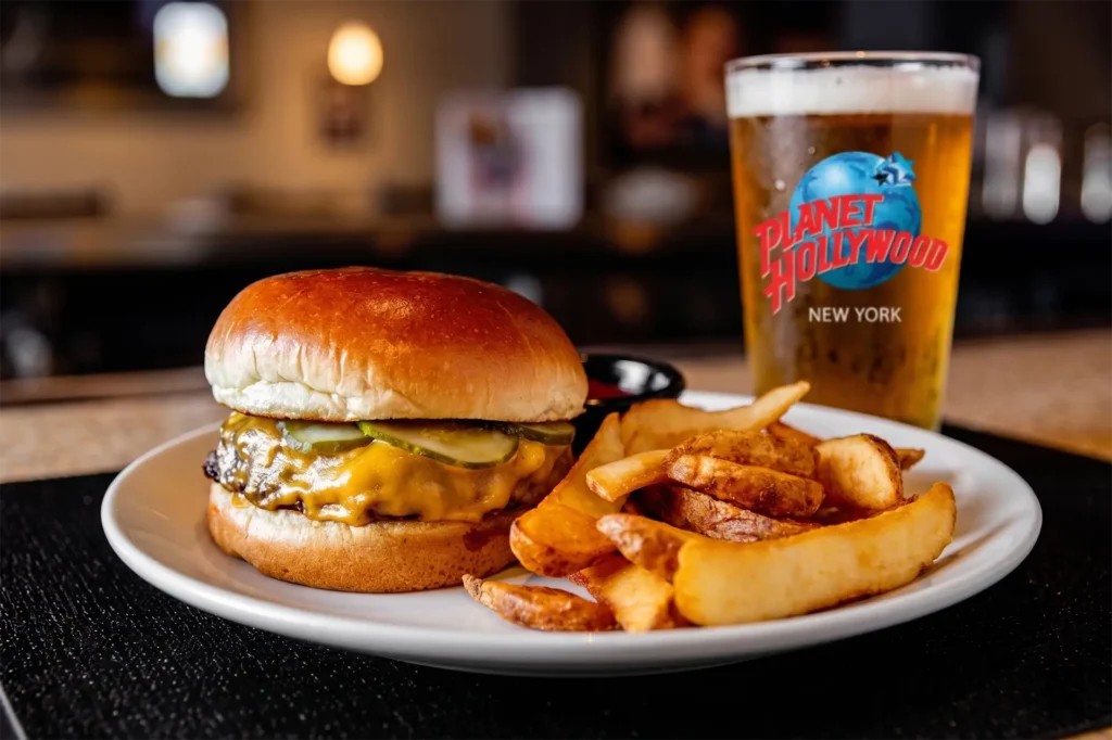 A cheeseburger with pickle, fries & a beer