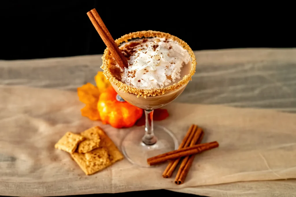 Pumpkin Pie Martini topped with whipped cream, cinnamon and a graham cracker rim with fall decorations.