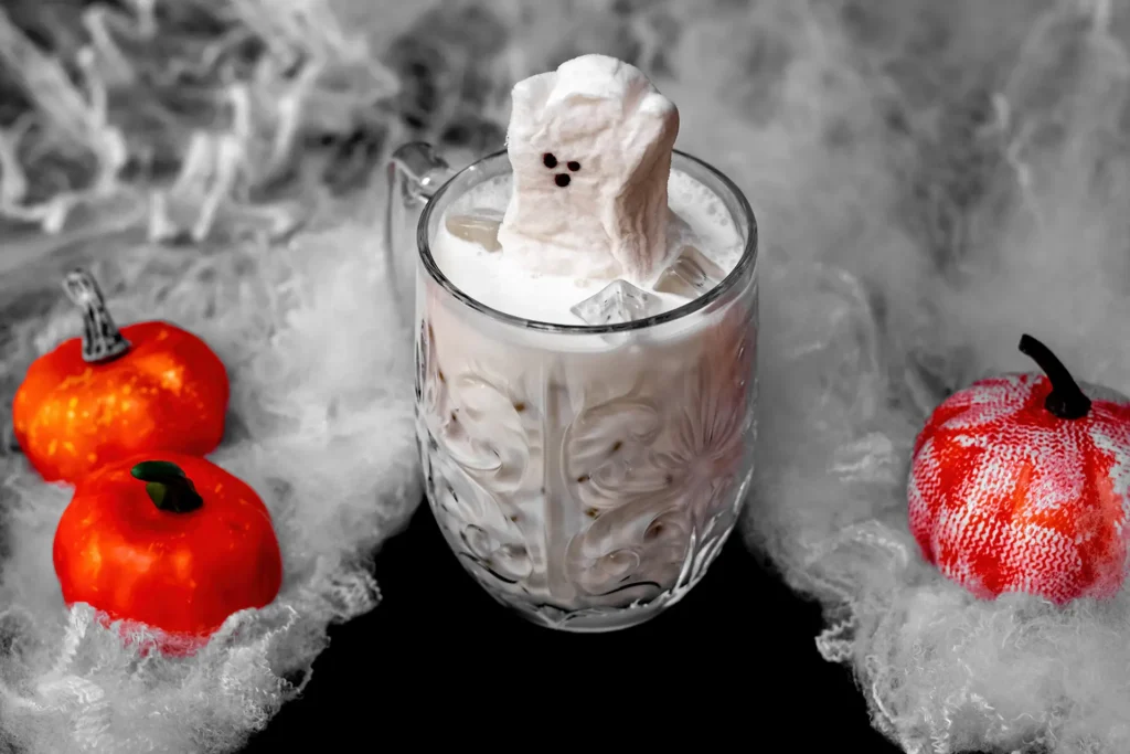 Casper the Ghost mocktail with coconut milk and a ghost-shaped garnish surrounded by Halloween pumpkins.